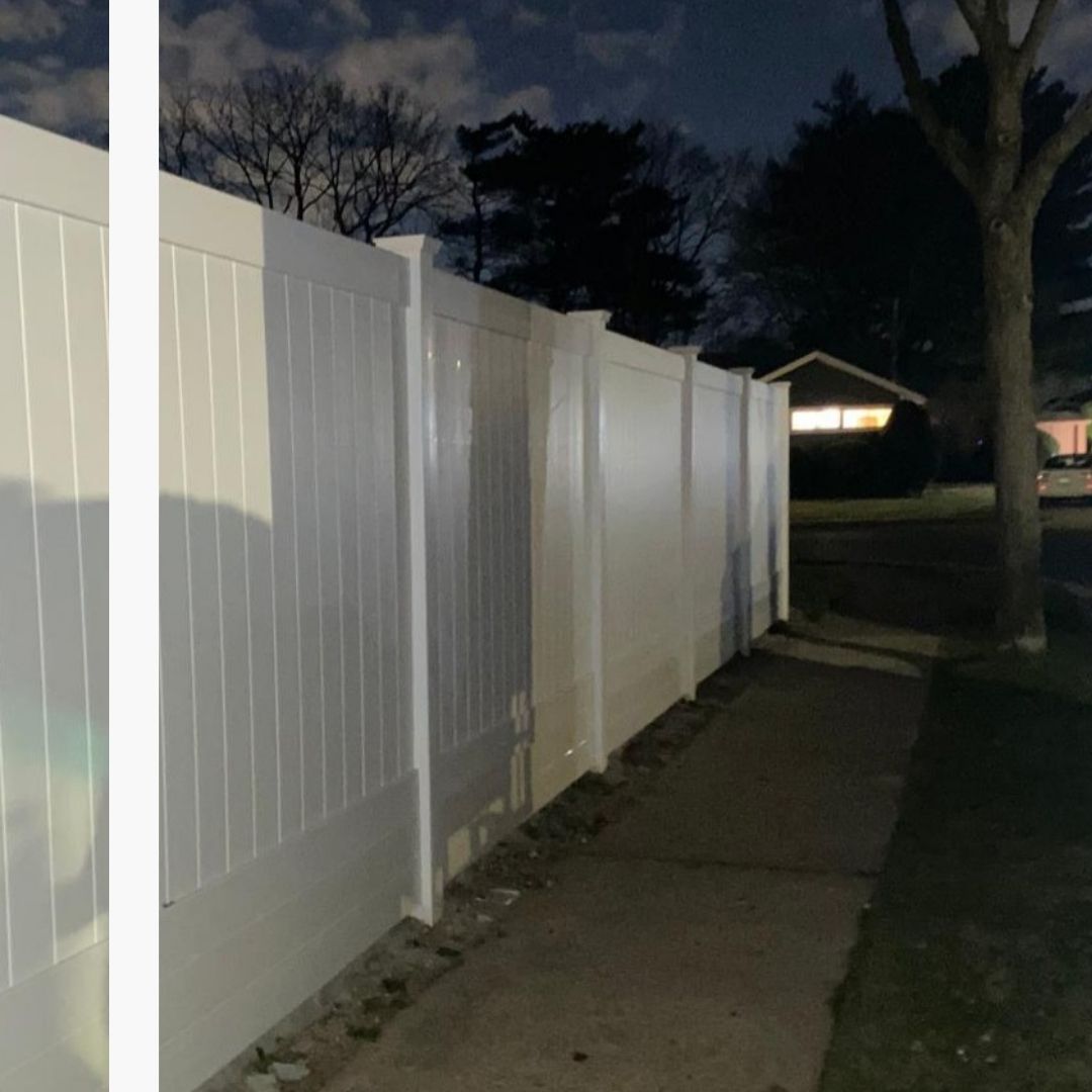 Professional white PVC vinyl privacy fence installation along a residential sidewalk at night.