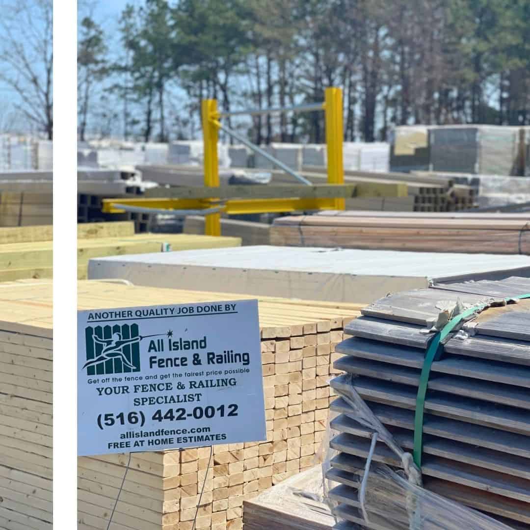 A business card for "All Island Fence & Railing" is propped up on a stack of lumber at a supply yard.