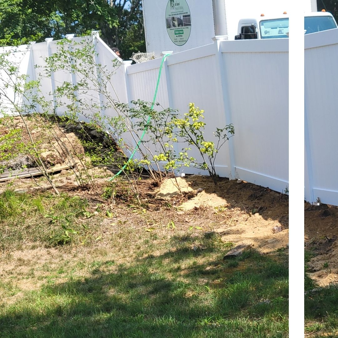 A white vinyl privacy fence installation by All Island Fence & Railing, shown stepping down a sloped, natural wooden area.